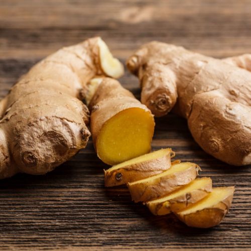 Fresh ginger, whole and sliced on rustic wooden background